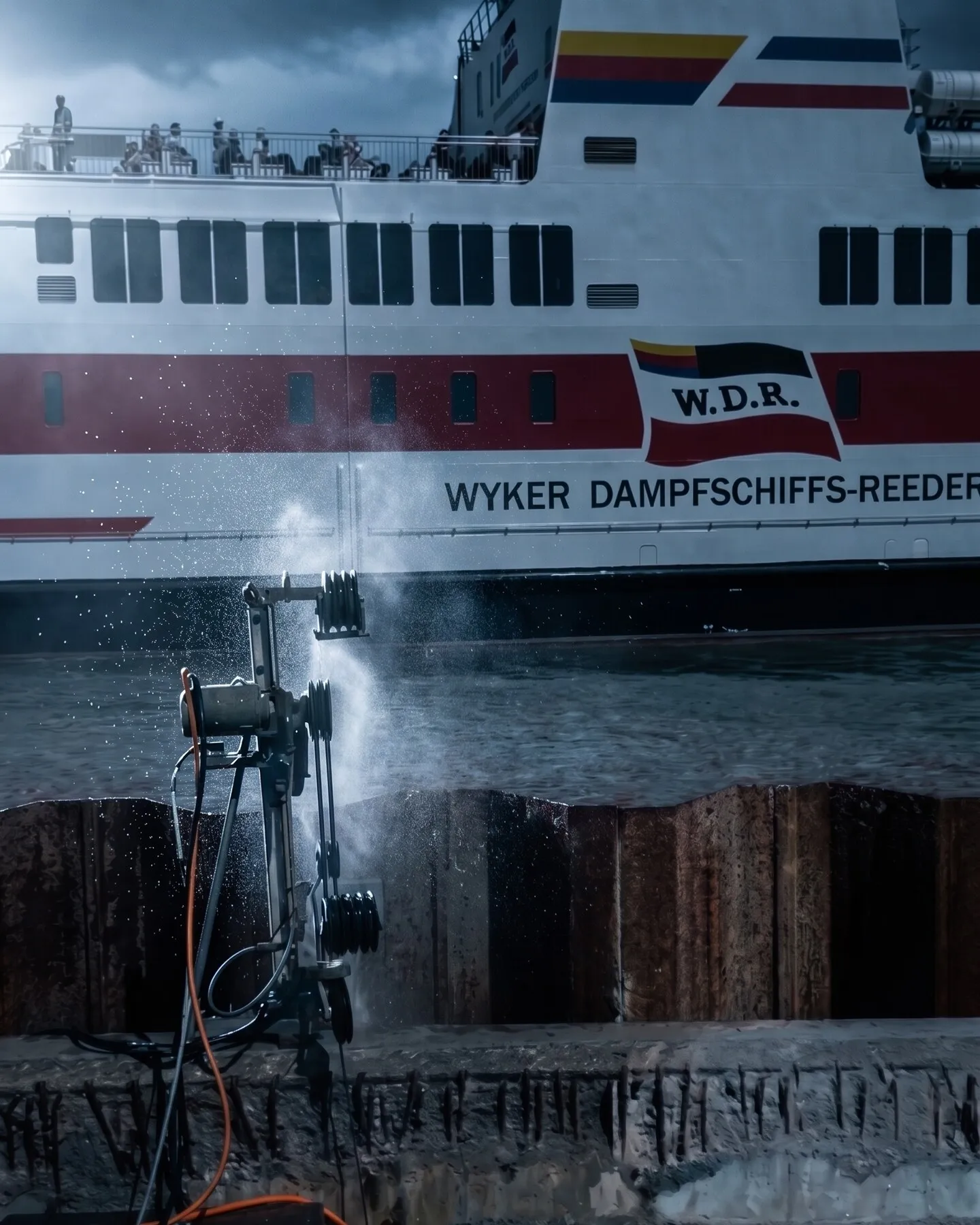 Wandsäge schneidet an der Kaimauer, dahinter liegt die Fähre der Wyker Dampfschiffs-Reederei