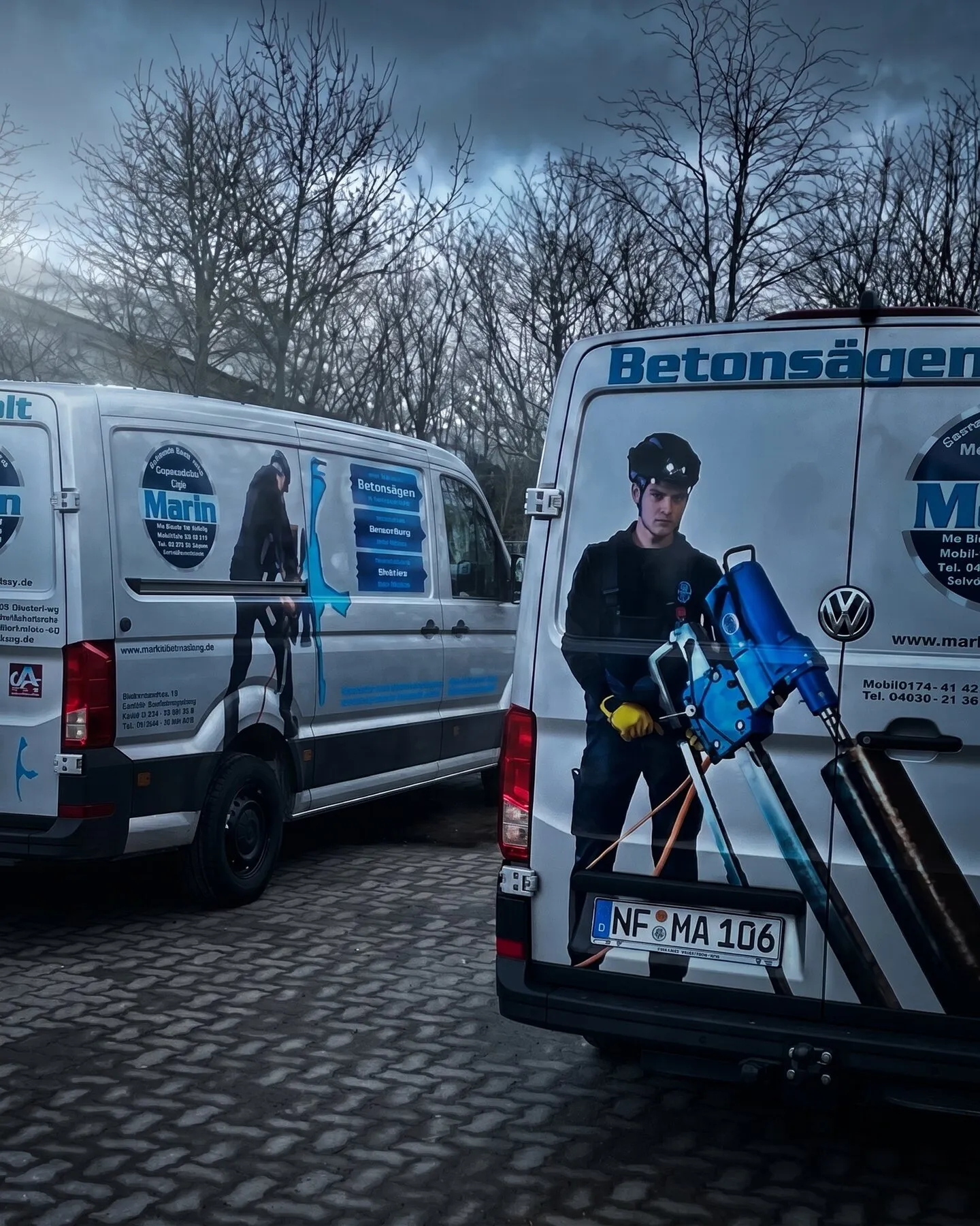 Zwei Transporter von Marin mit Firmenbeschriftung auf dem Hof